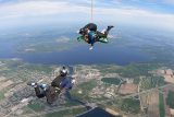 Outside view of a videographer capturing a tandem skydiving student and instructor in freefall