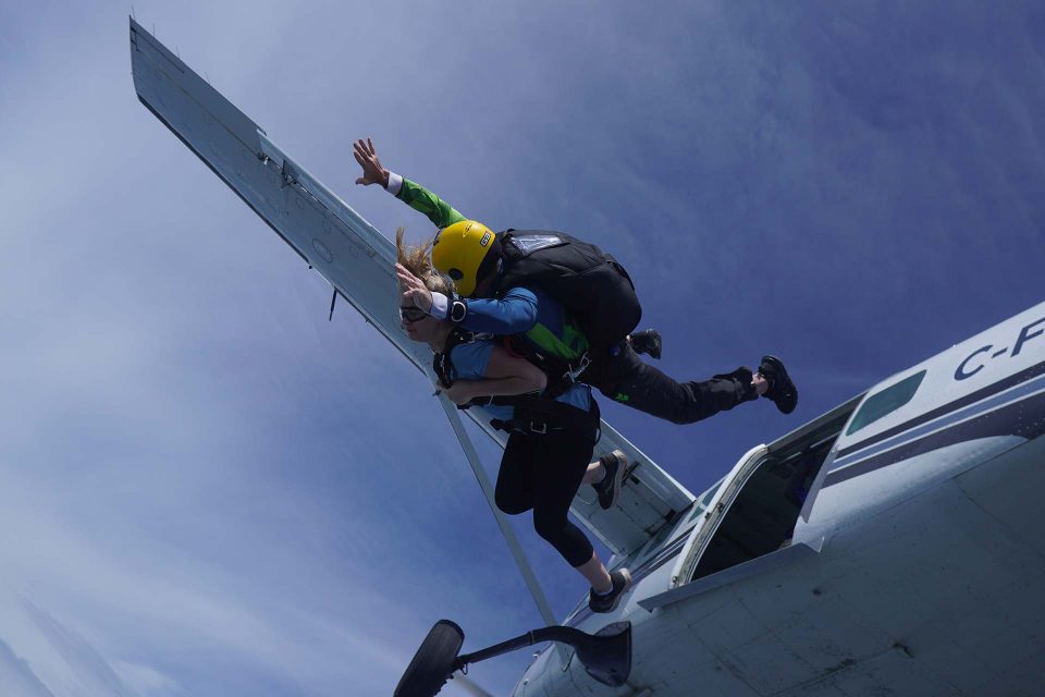 Tandem skydiving student and instructor exiting an airplane above Parachute Ottawa